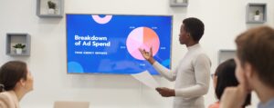 article banner image featuring a marketer looking at a powerpoint presentation with a breakdown of ad spend