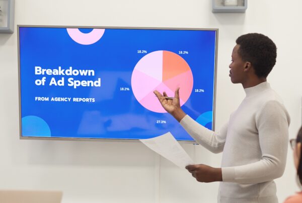 article banner image featuring a marketer looking at a powerpoint presentation with a breakdown of ad spend