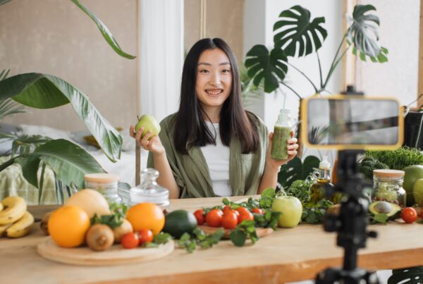 article banner featuring asian woman cooking healthy foods in front of a camera The Role of Influencers in the Women's Health Industry