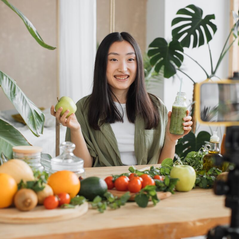 article banner featuring asian woman cooking healthy foods in front of a camera The Role of Influencers in the Women's Health Industry