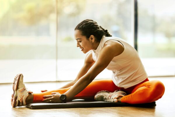 Wellness Marketing Services: Key Benefits to Consider article banner image featuring a woman stretching on a yoga mat