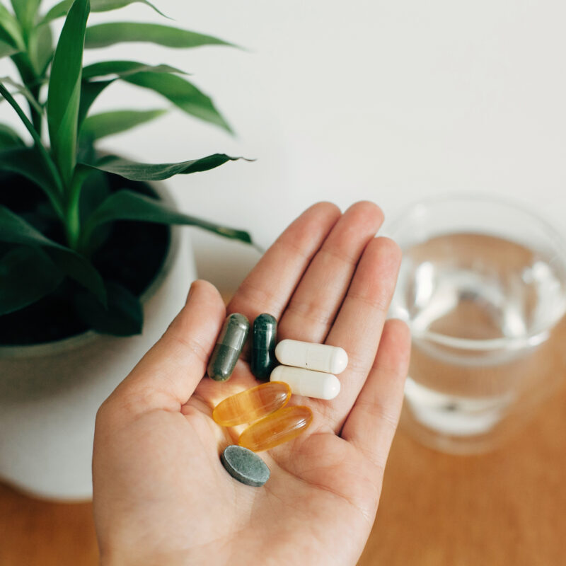 How to Master Supplement Marketing Compliance Without Losing Conversions article banner featuring a woman's hand holding supplements