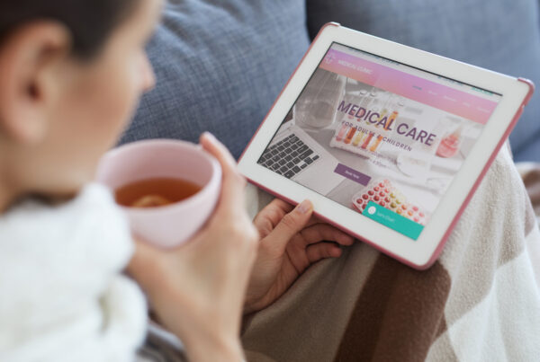 How Brands Can Reach the True Healthcare Decision Maker article banner featuring a woman drinking tea and looking at a tablet with medical care options for her family